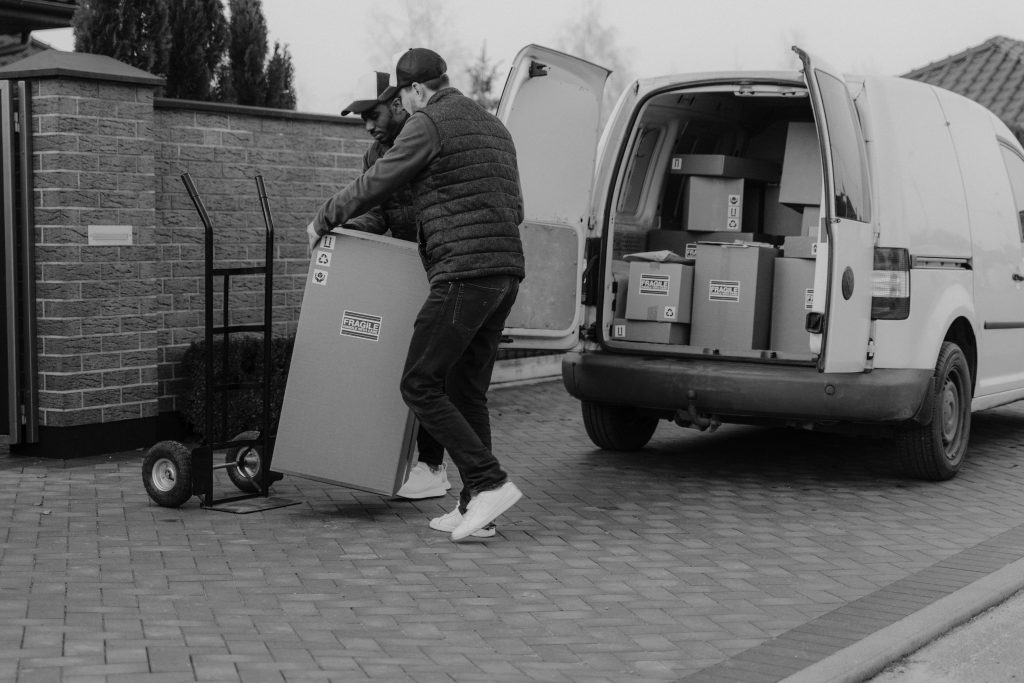 Two men unloading fragile packages from a delivery van, showcasing teamwork in logistics.