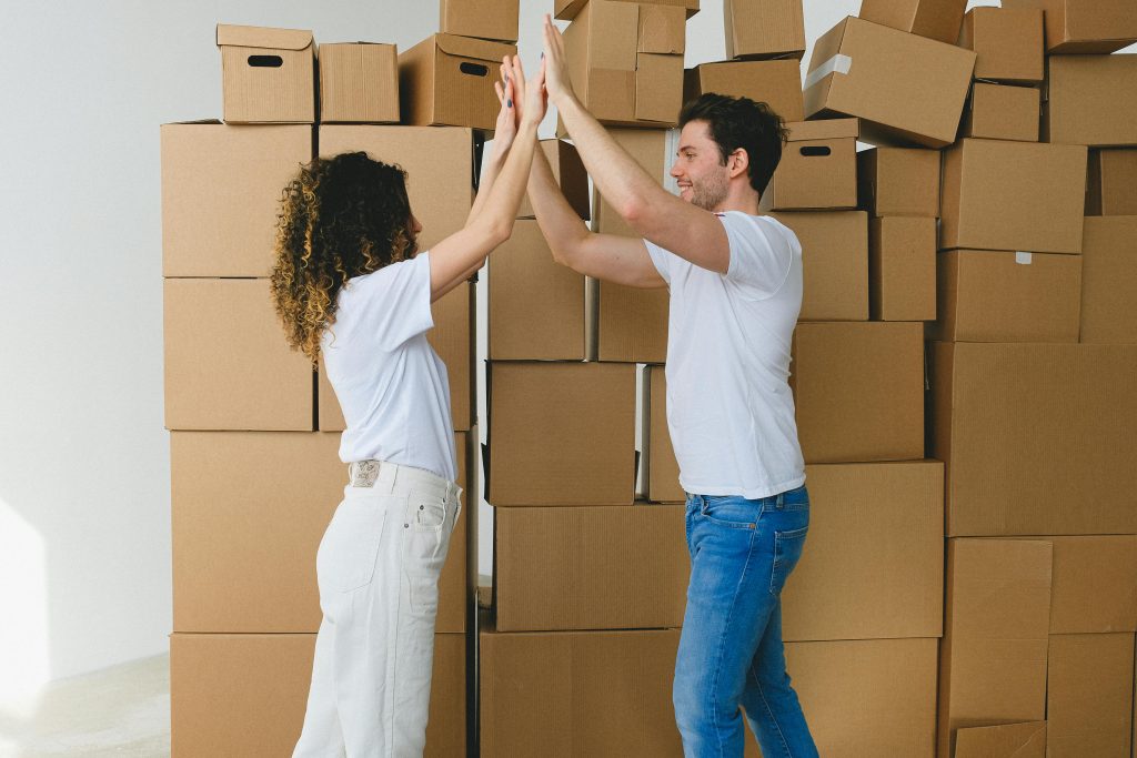 Joyful couple high-fiving in their new home surrounded by moving boxes.